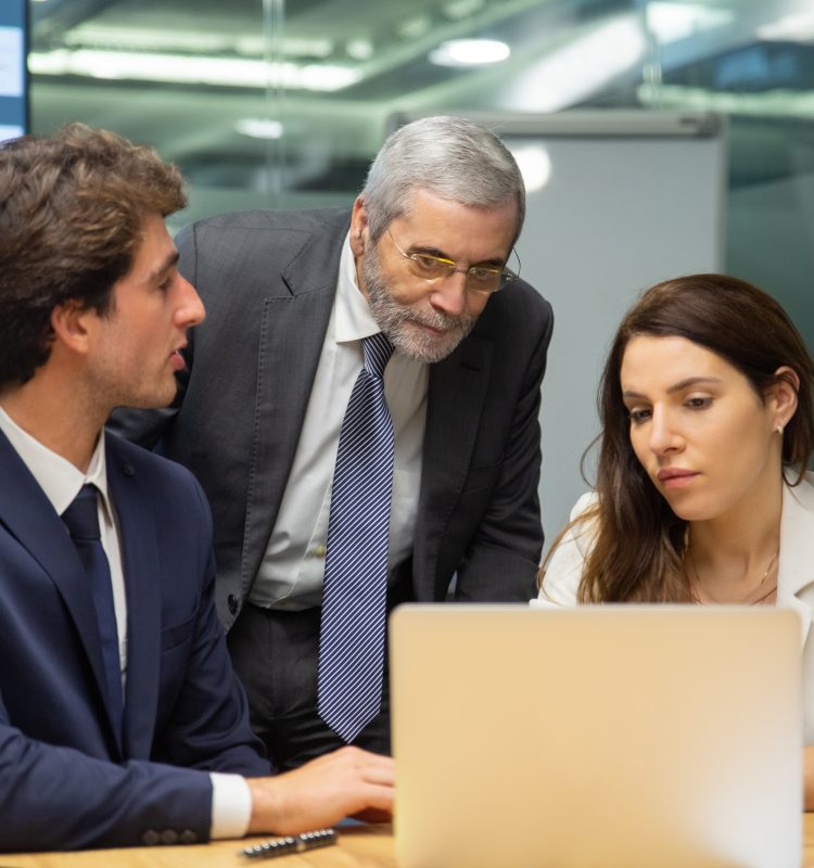 Front view of confident business team looking at laptop. Group of office employees sitting at table and discussing new project. Business, teamwork concept